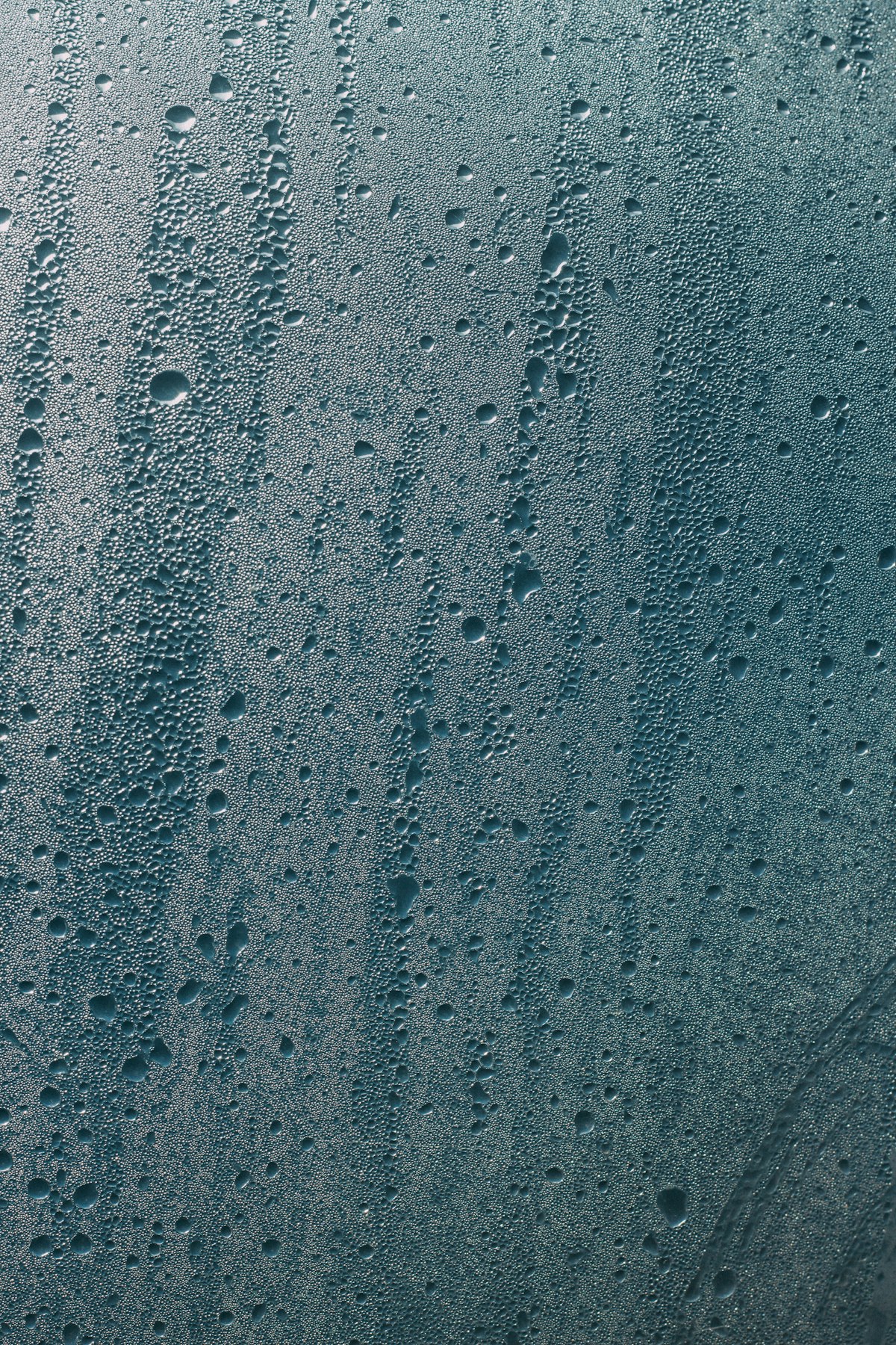 Close-up of water droplets and condensation running down a window pane