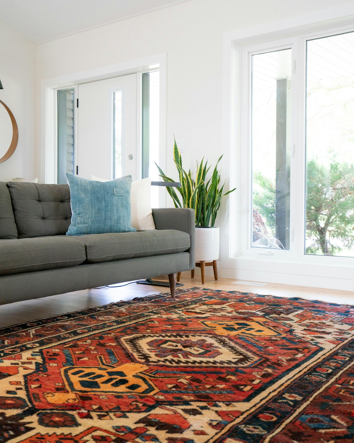 A teal sofa on a large patterned rug in a bright living room