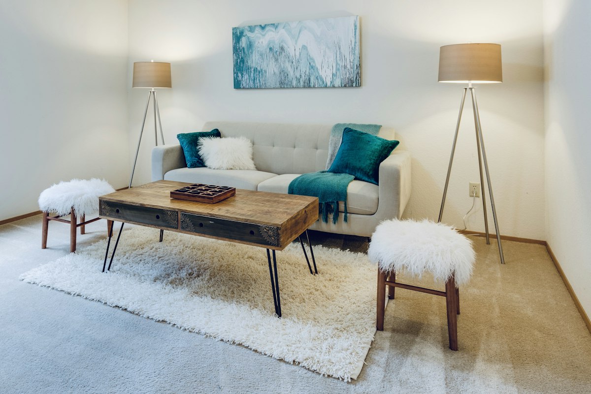 A pale cream living room with a rug, coffee table and two floor lamps
