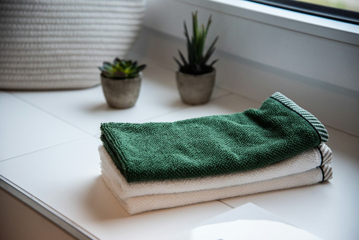 Dry folded towels on a white windowsill beside small plants