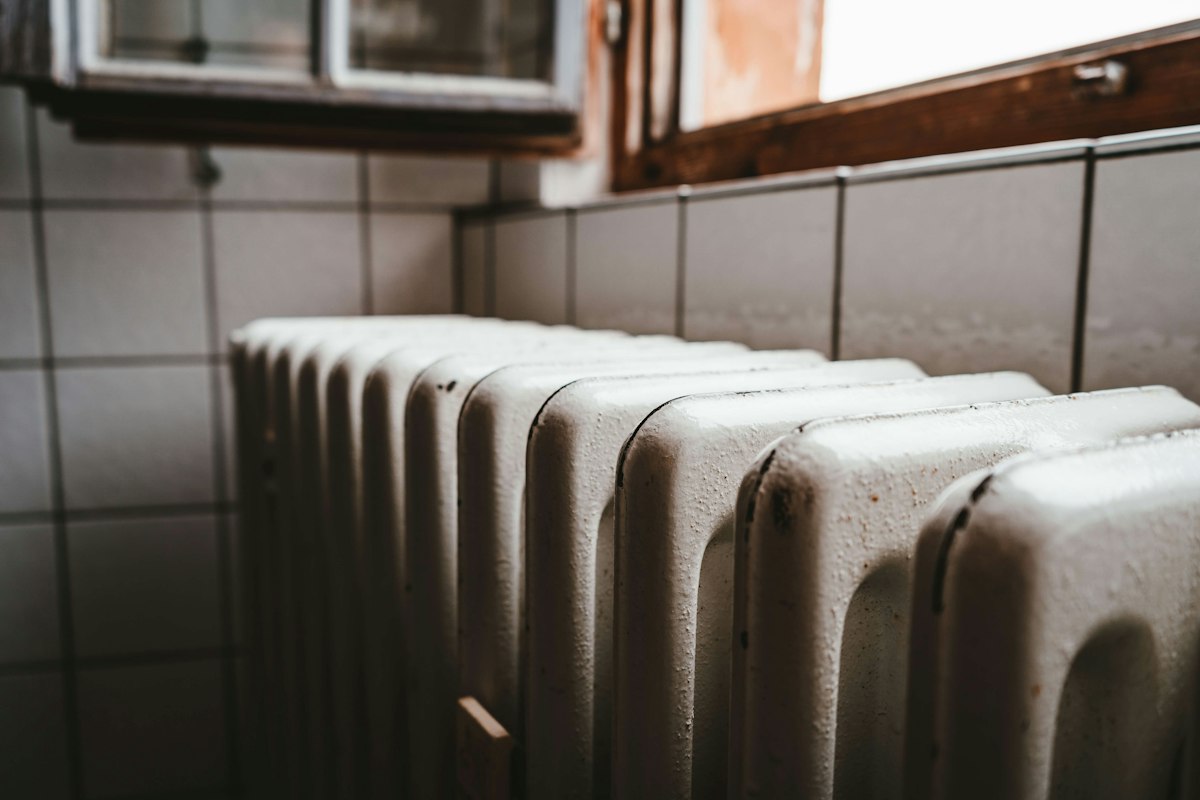 An old white cast-iron radiator beneath a window