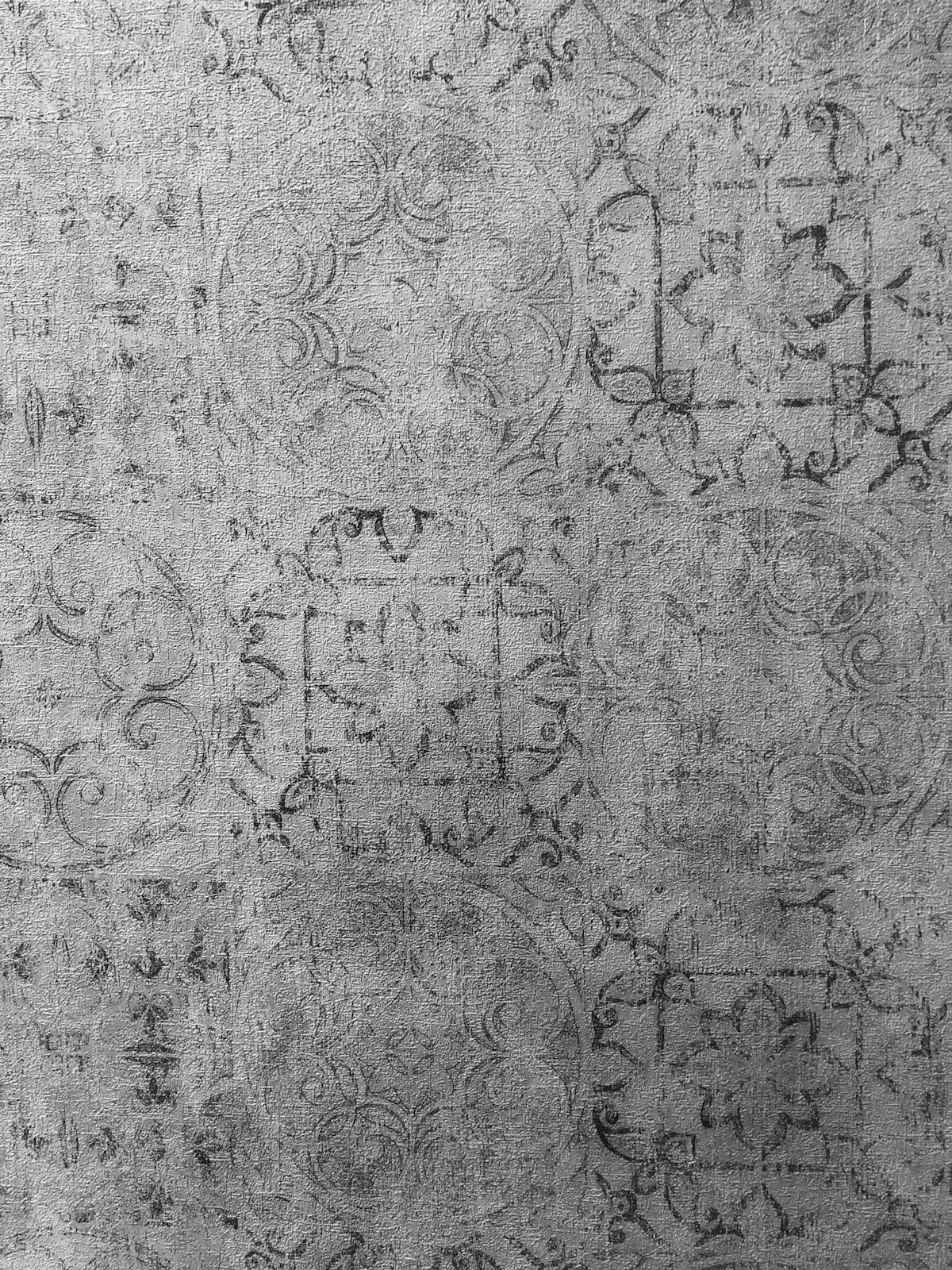 A grey wall with a repeating damask pattern