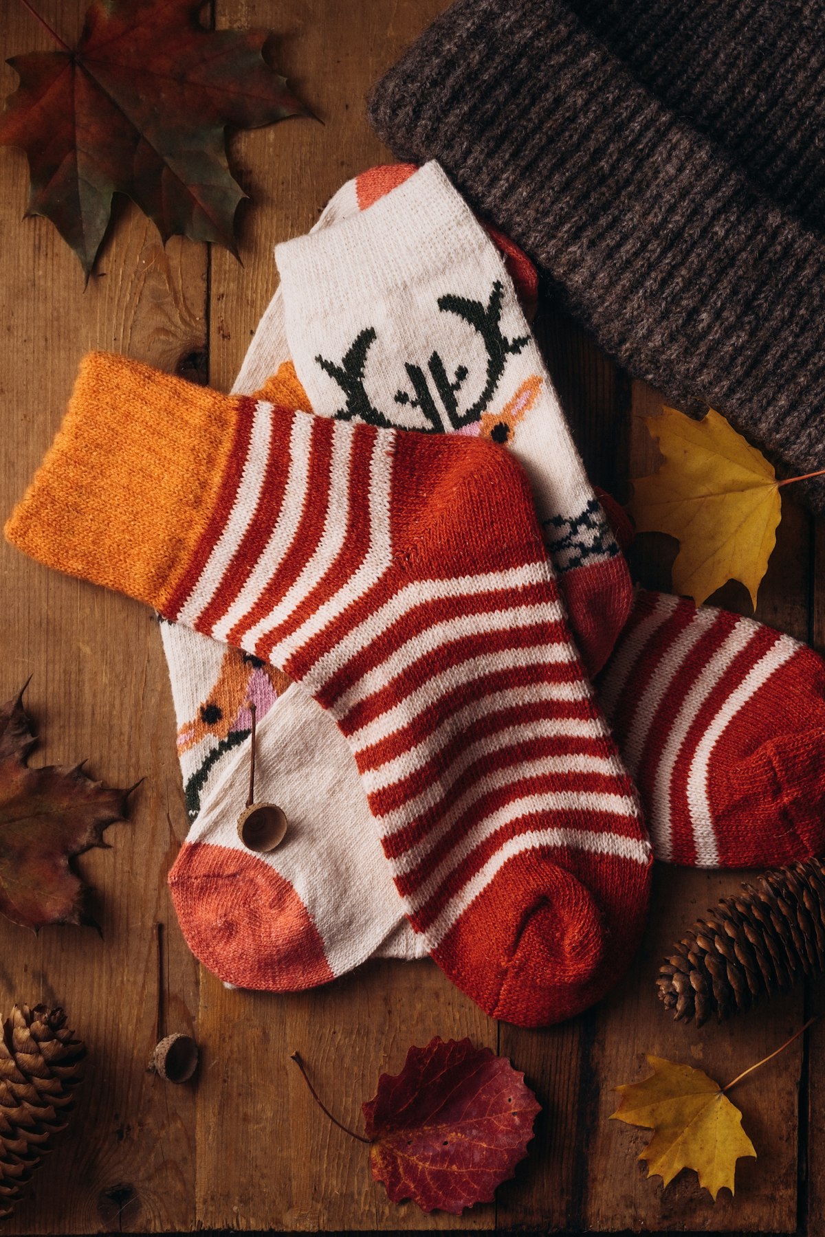 Red and white striped knitted socks and a hat on a wooden table
