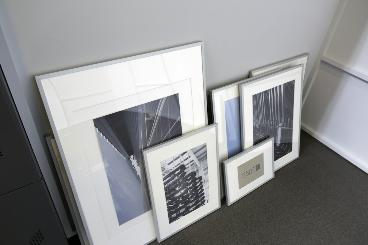 Several framed black-and-white prints leaning against a pale wall