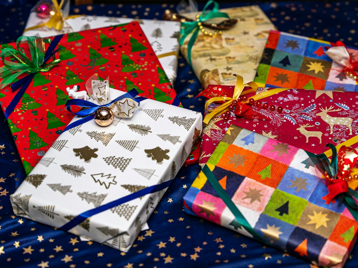 A pile of Christmas presents in patterned wrapping paper on a table
