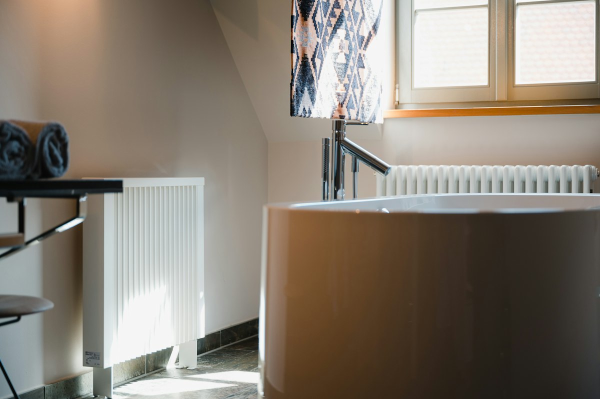 A bright bathroom with a bath and a white radiator