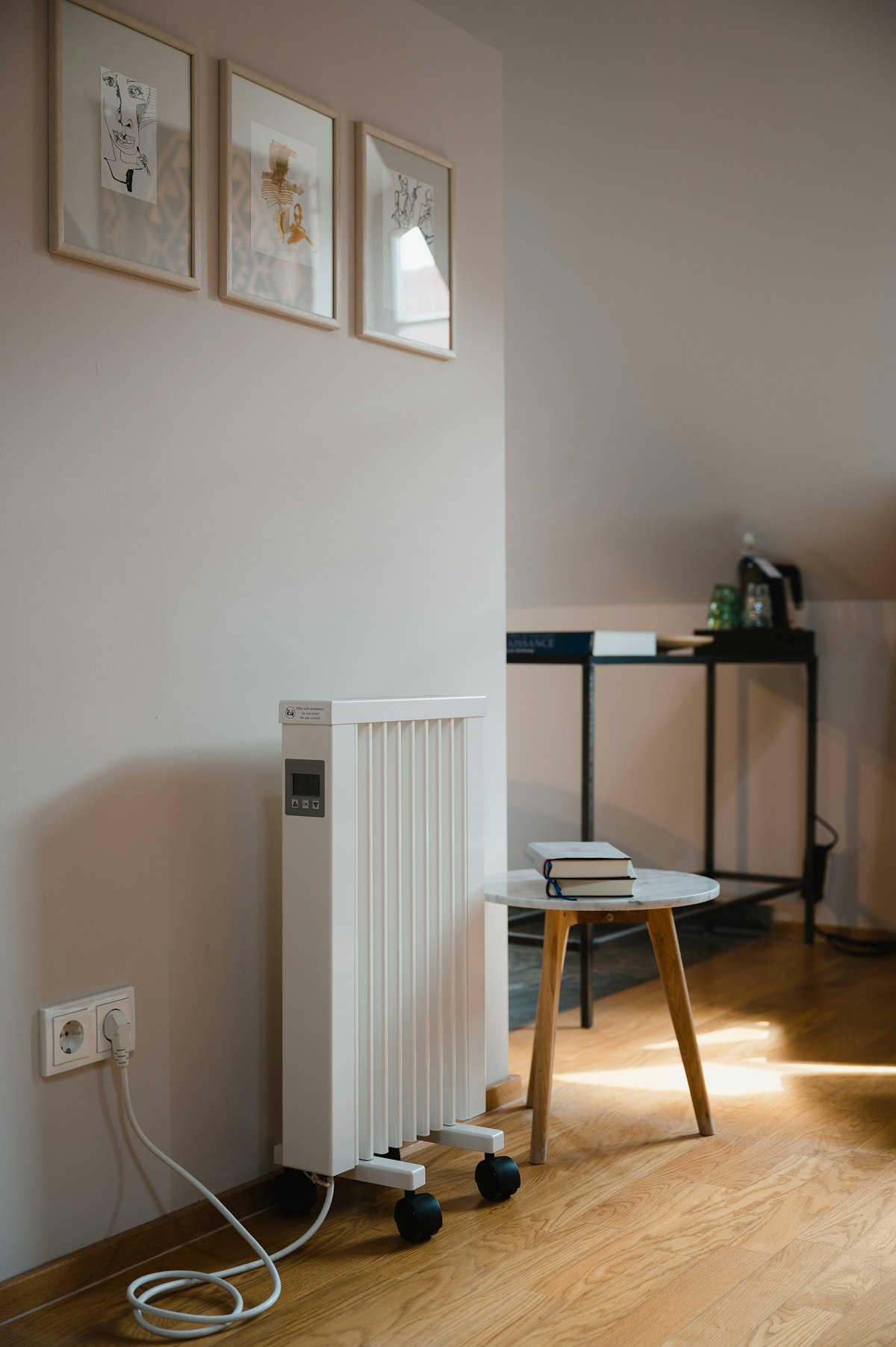 A slim plug-in electric heater beside a side table in a bright room