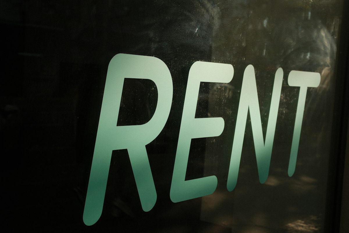 The word RENT in large letters on a dark glass window